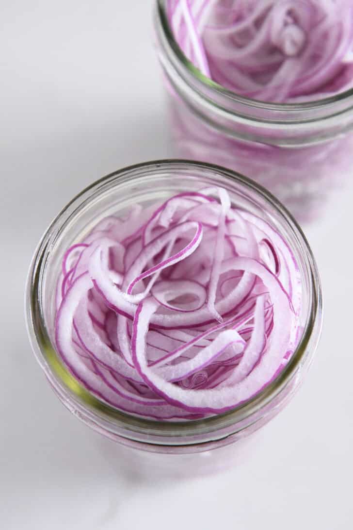 Top down view of pint jar with thinly sliced red onions.