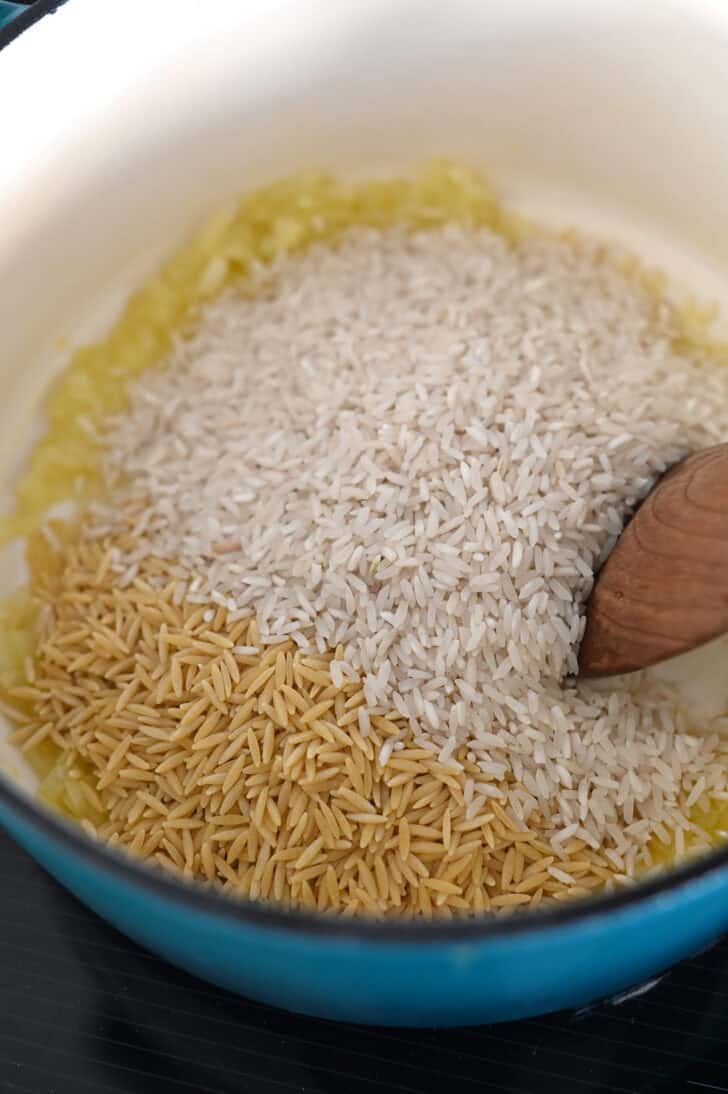 Long grain white rice and orzo pasta in butter and onions in cast iron pot.