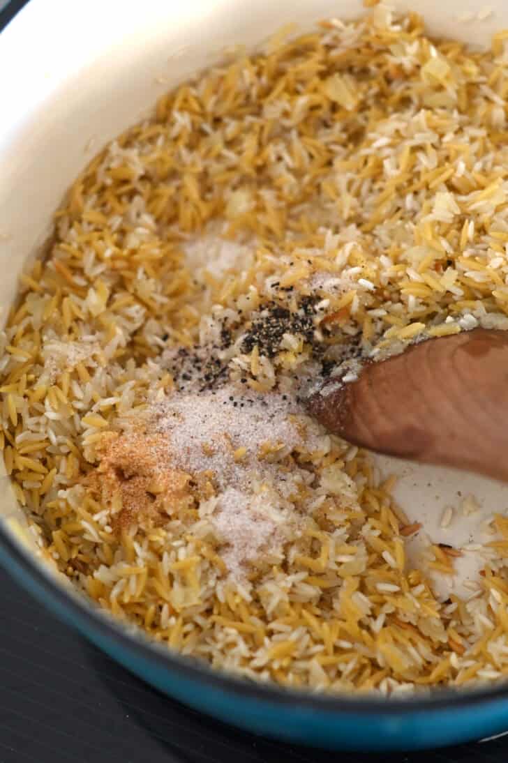 Garlic powder, onion powder, salt and pepper in pot with rice, orzo and butter.