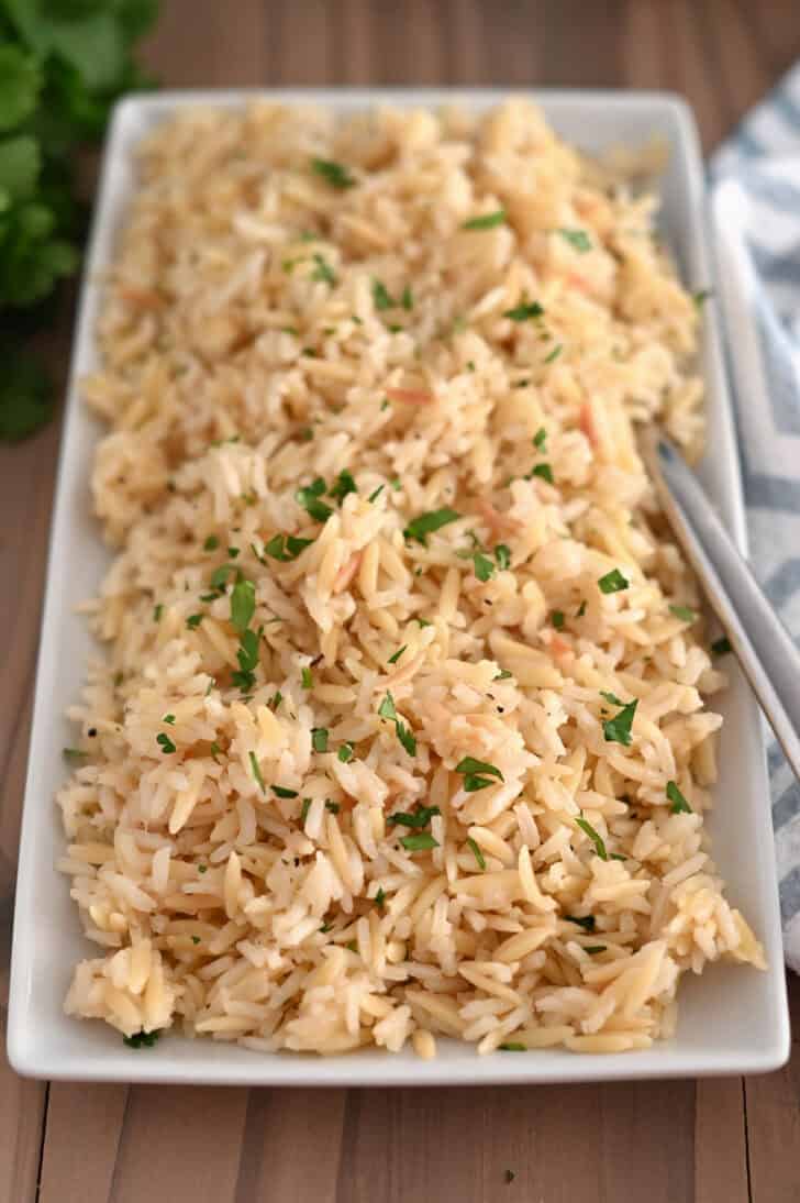 Top down view of rice pilaf with fresh parsley on white tray.