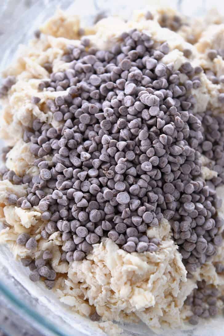 Top down view of a glass bowl of scone dough and cinnamon chips.