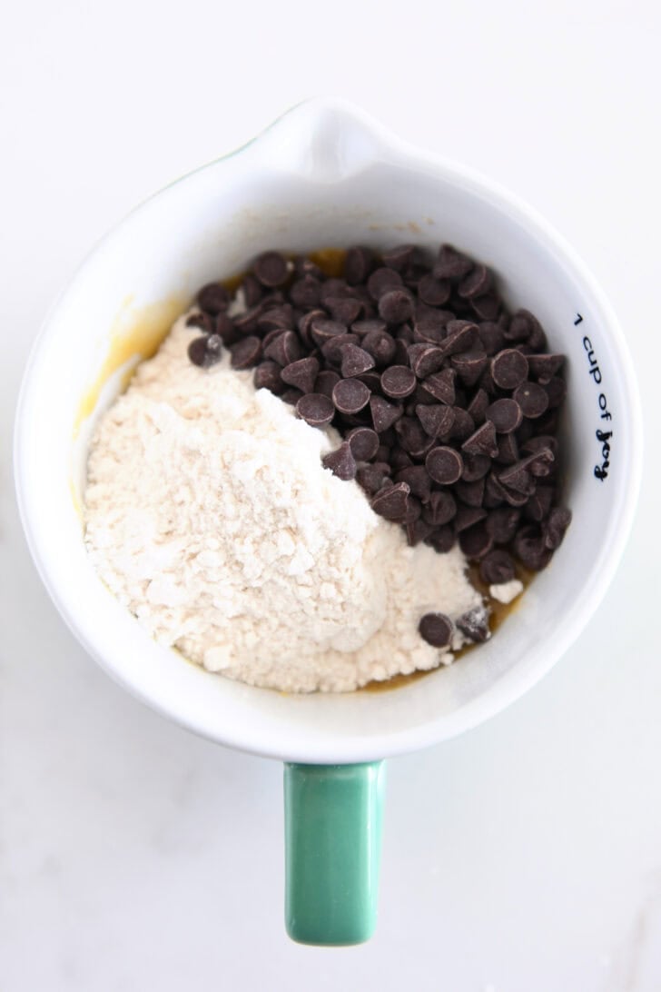 Top down view of flour and chocolate chips in mug.