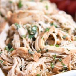 Close up view of shredded chicken topped with chopped cilantro.