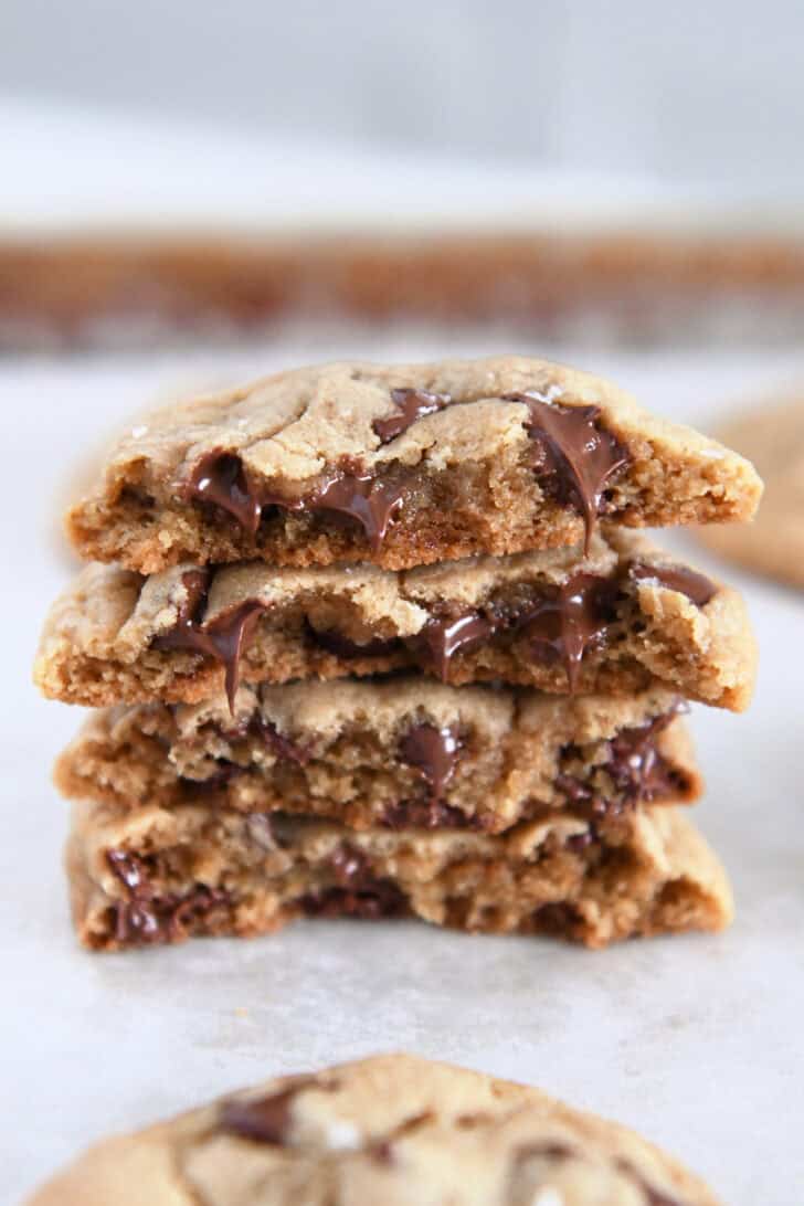 Four half cookies stacked on each other on parchment lined baking sheet.