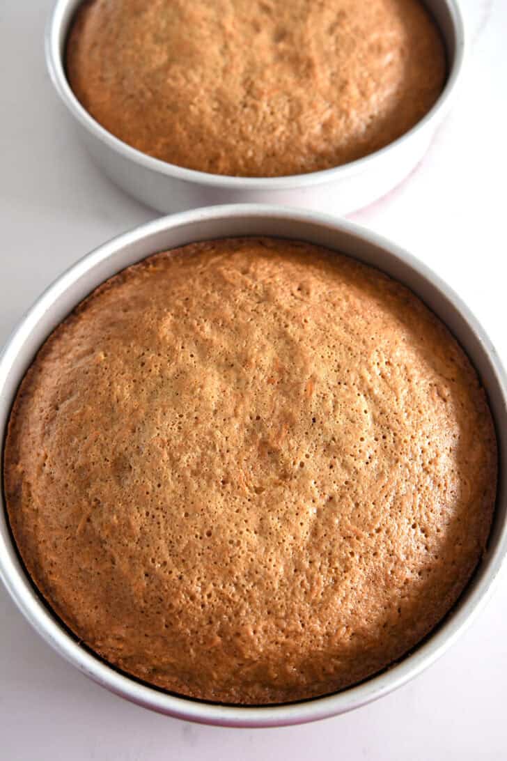 Two 9-inch round cake pans with baked carrot cake layers.