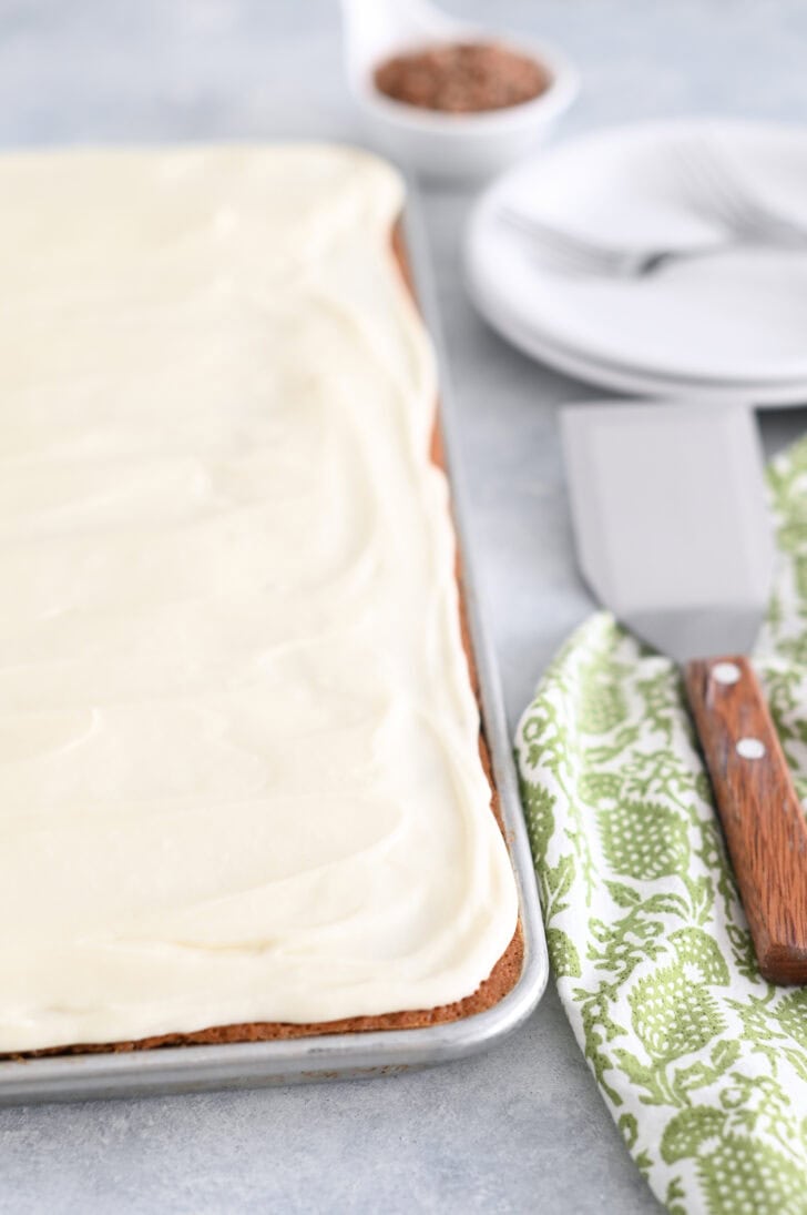 Top down view of a sheet pan of frosted carrot sheet cake.