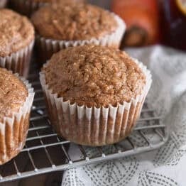 Several baked carrot cake muffins on wire cooling rack.