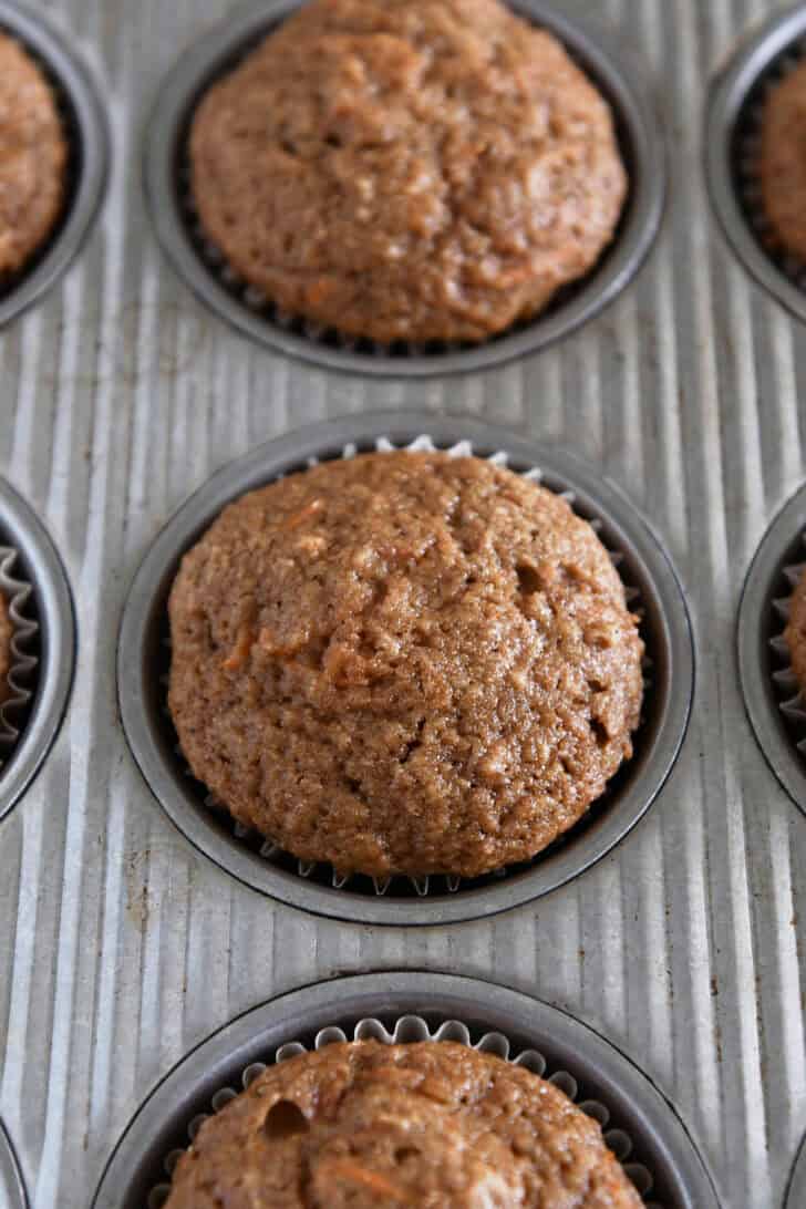Baked carrot cake muffins in lined muffin tins.