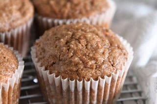 Several baked carrot cake muffins on wire cooling rack.