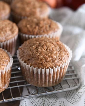 Several baked carrot cake muffins on wire cooling rack.