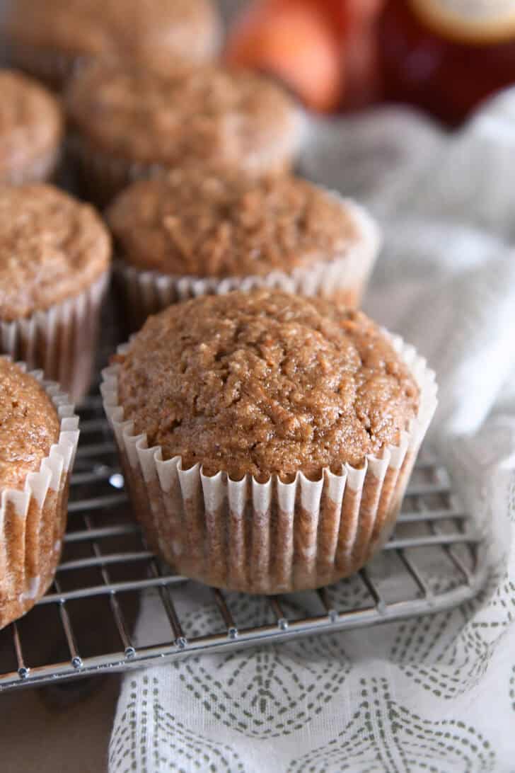 Several baked carrot cake muffins on wire cooling rack.