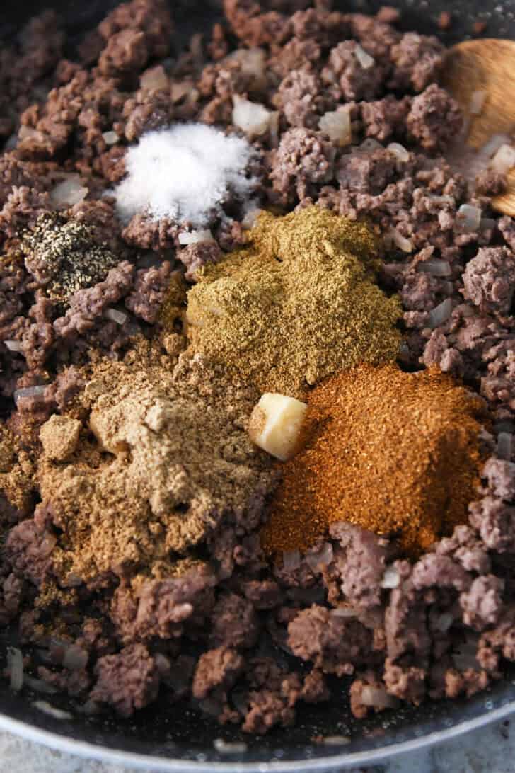 Top down view of cooked ground beef with seasonings poured in the middle.