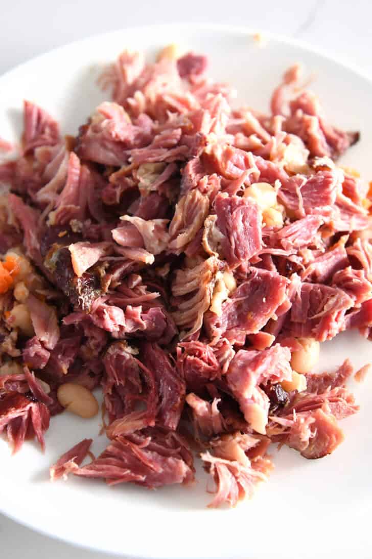 Shredded ham pieces on white plate.