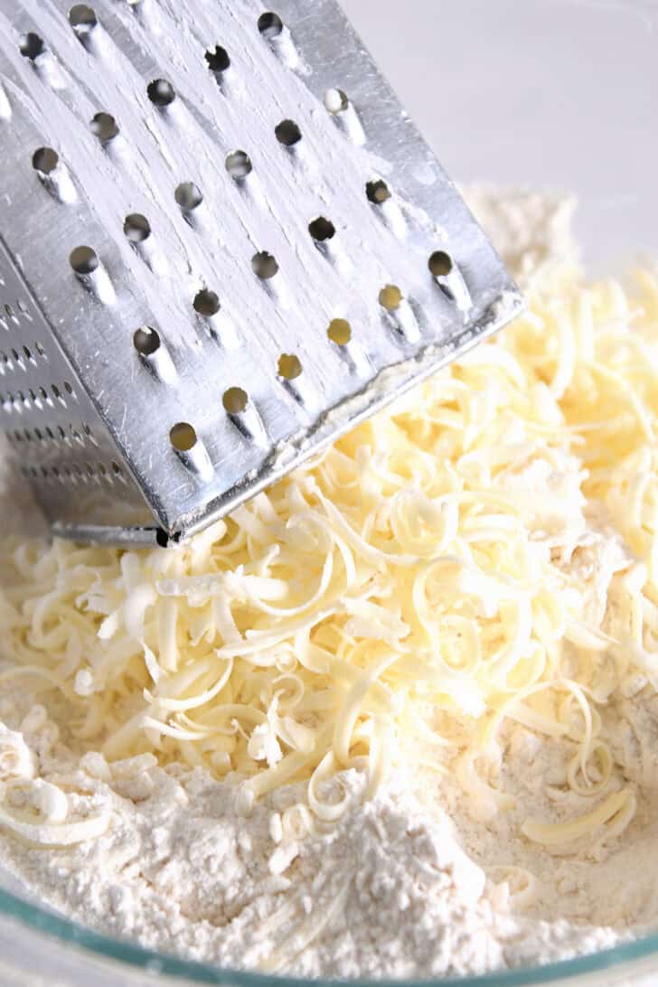 Grated butter shreds in bowl with dry ingredients.