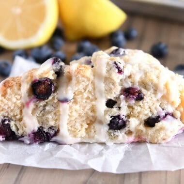 One triangle-shaped lemon blueberry scone on white parchment paper.