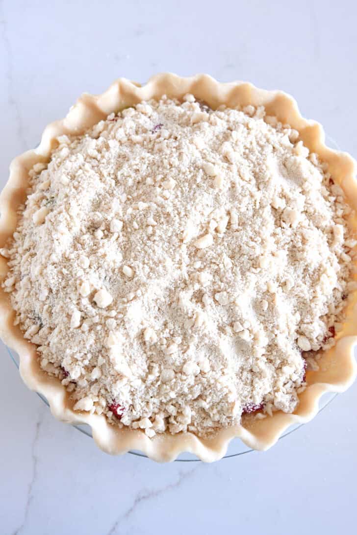 Streusel topping covering the top of unbaked strawberry rhubarb pie.