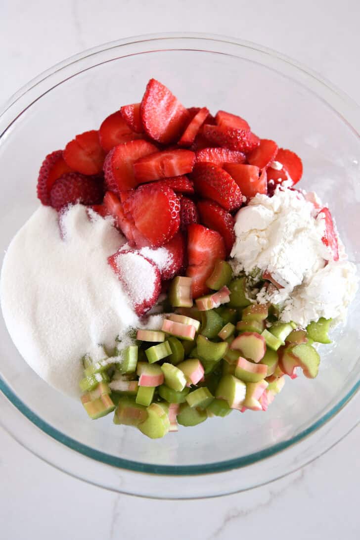 Glass bowl with strawberries, rhubarb, cornstarch and sugar.