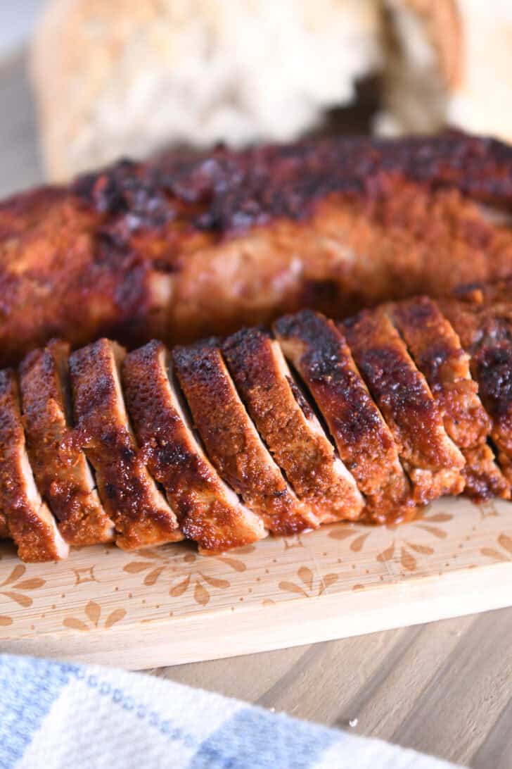 Slices of air fryer pork tenderloin on wood cutting board.