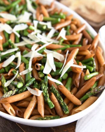 White serving dish with balsamic penne pasta, roasted asparagus and parmesan cheese.