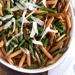 White serving dish with balsamic penne pasta, parmesan cheese and roasted asparagus.