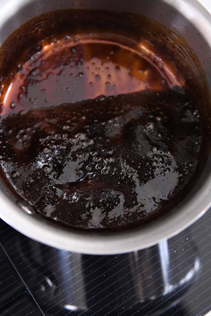 Thick reduced balsamic vinegar in small stainless pot.