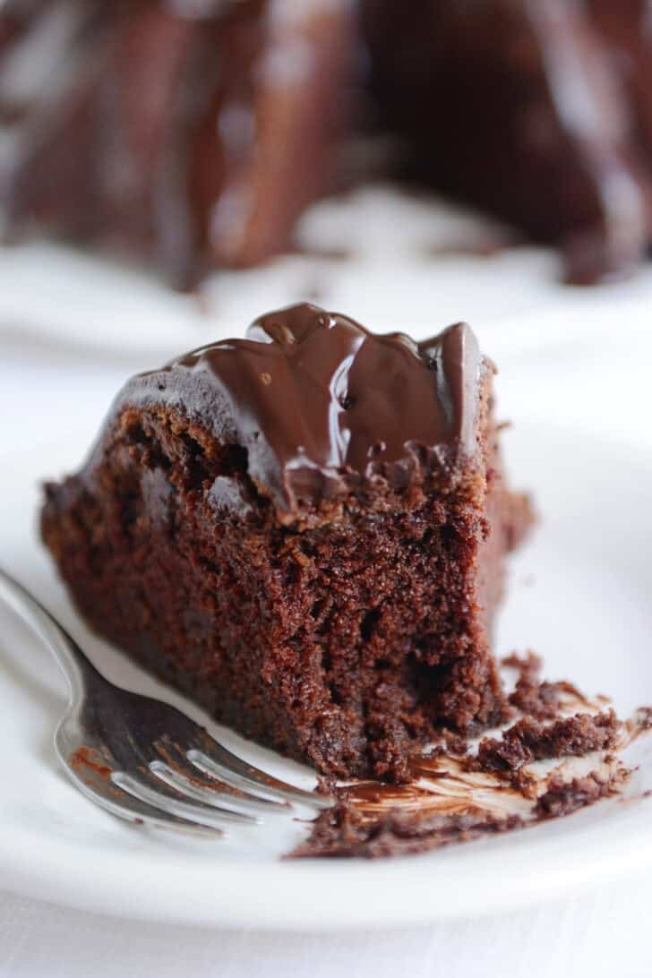 Slice of chocolate bundt cake with bite taken out on white plate.