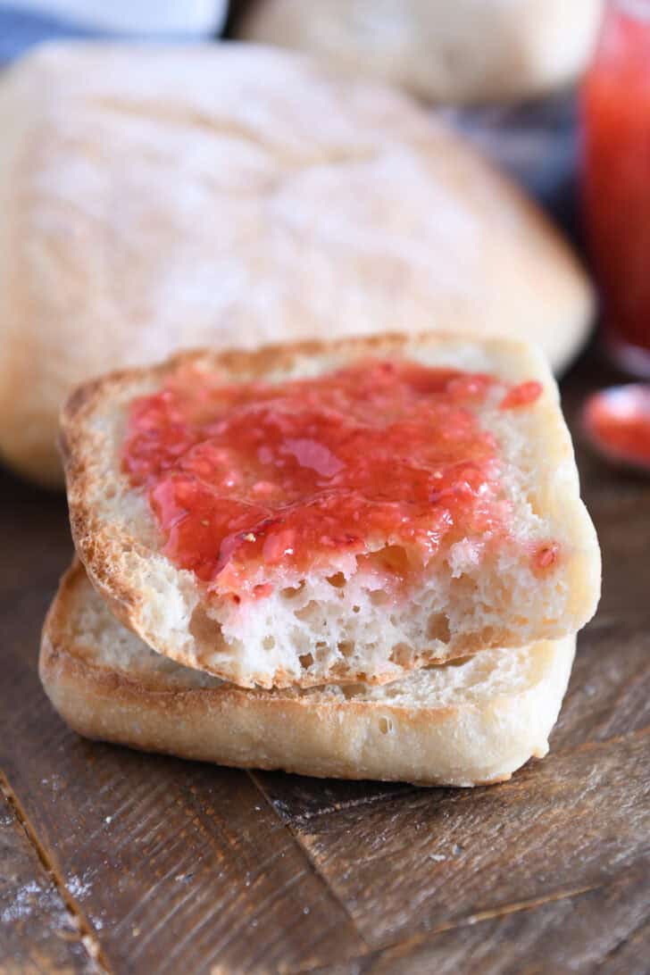 One half of ciabatta roll toasted and spread with butter and jam.