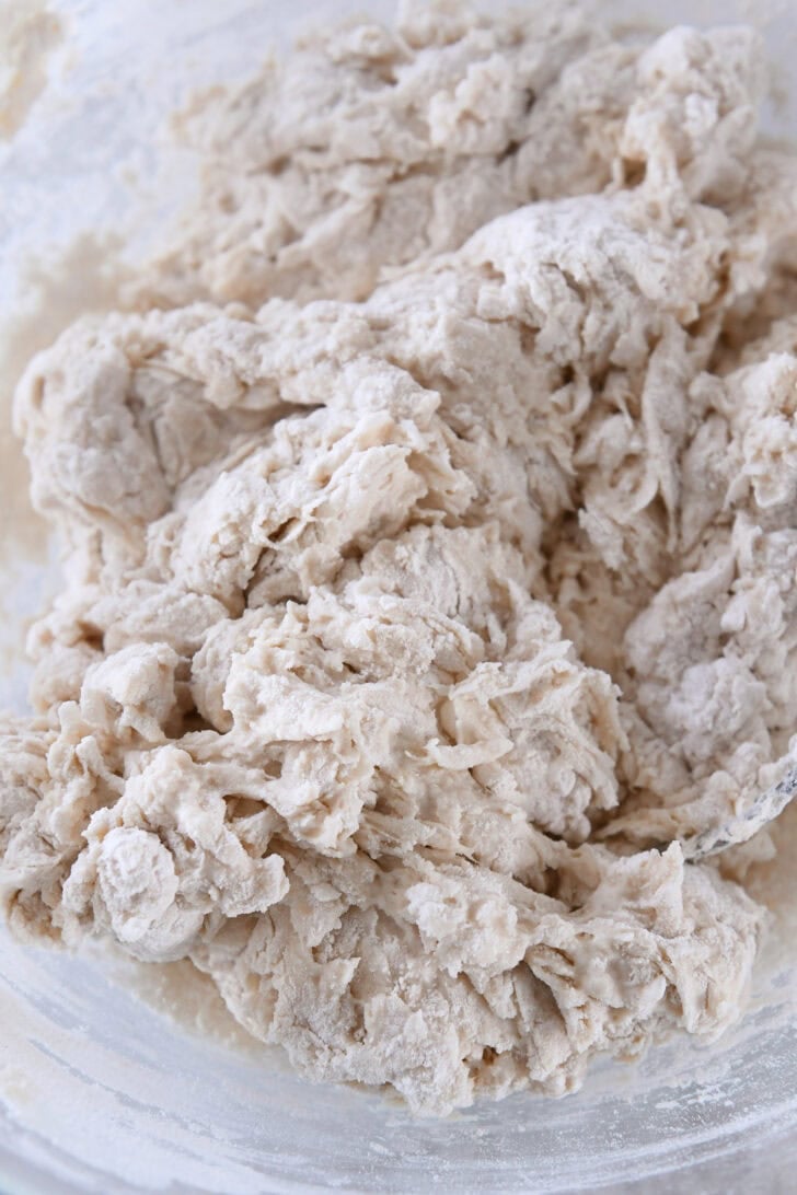 Glass bowl with shaggy ciabatta dough not fully mixed.