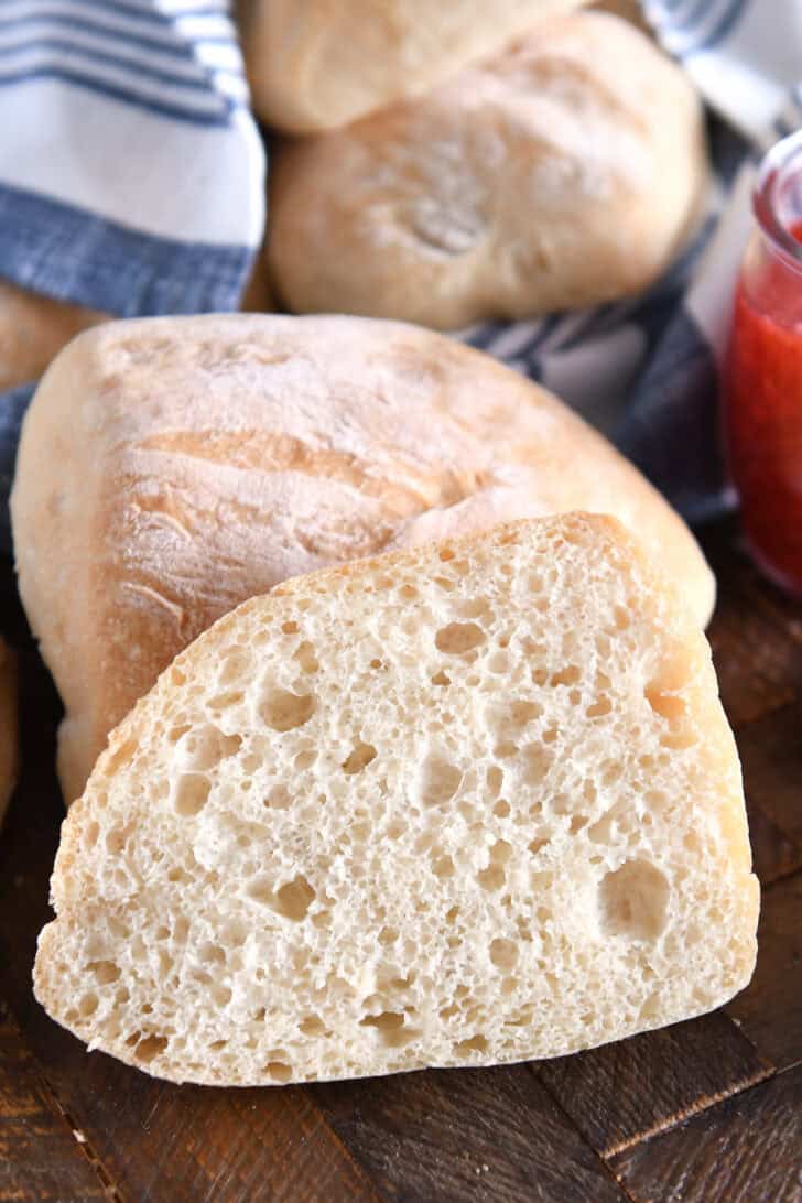 Cut side of half ciabatta roll with fluffy crumb and airy holes.