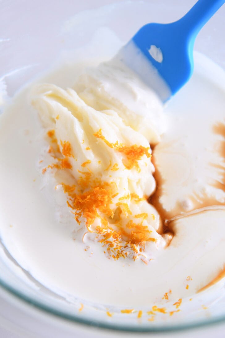 Heavy cream, orange zest, and cream cheese filling in glass bowl.