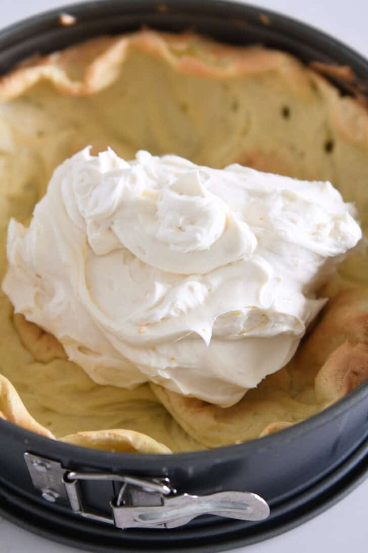 Cream cheese filling piled in cream puff shell in springform pan.