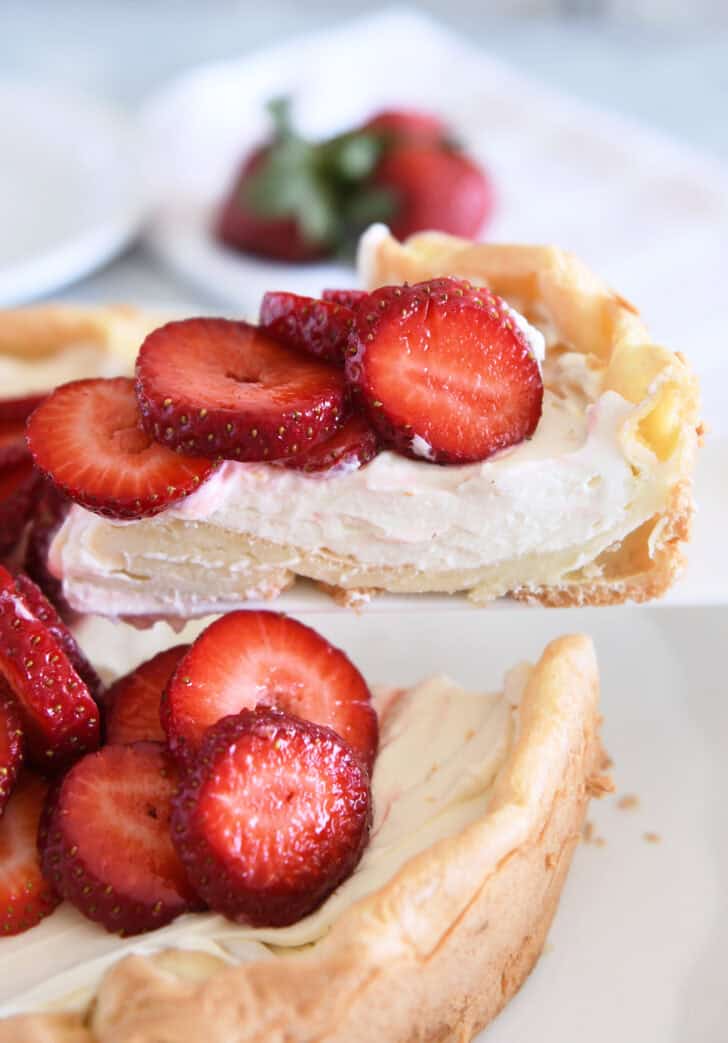 Slice of strawberry cream puff cake on white cake server.