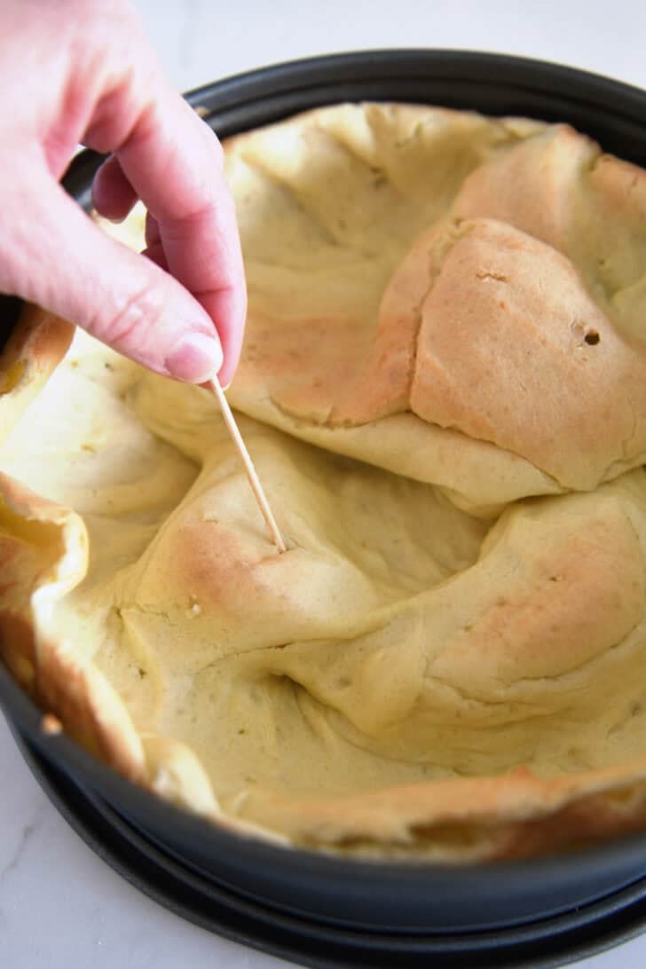 Piercing baked cream puff shell with toothpick.