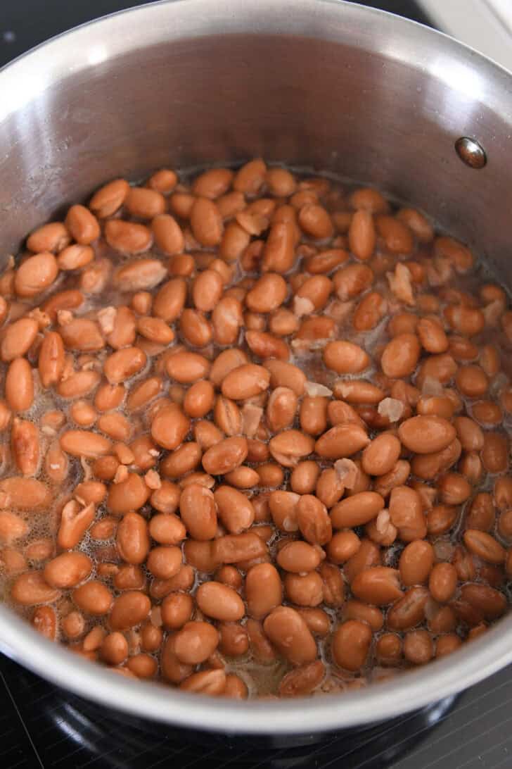Stainless pot with broth and canned beans.