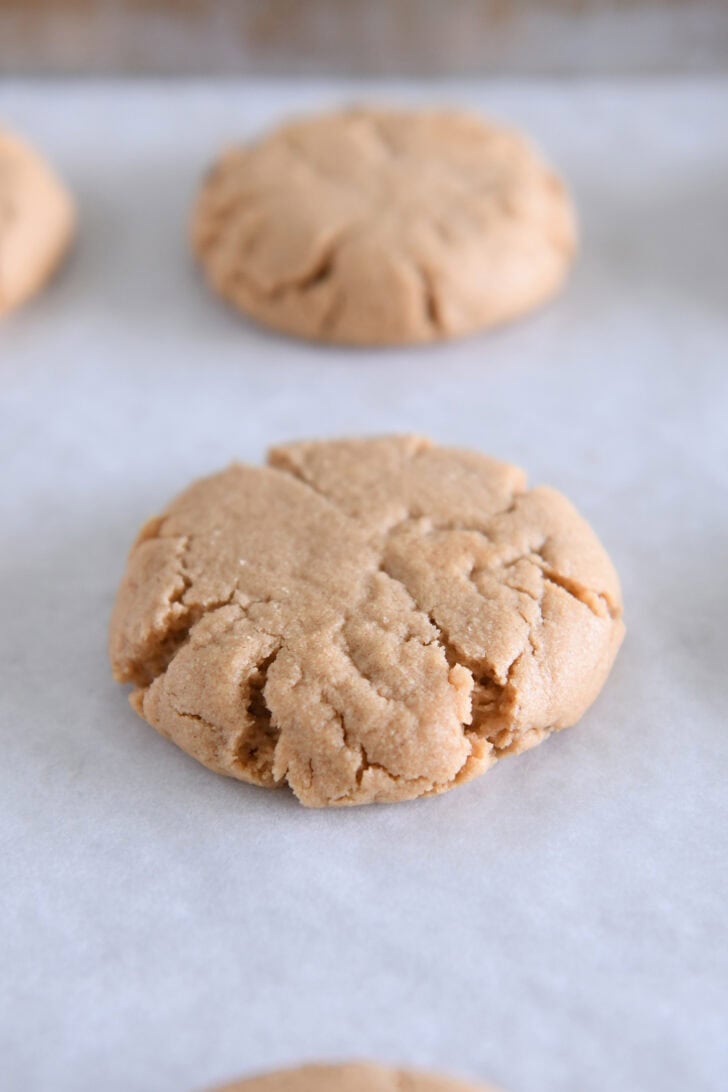 Baked peanut butter cookie on white parchment paper.