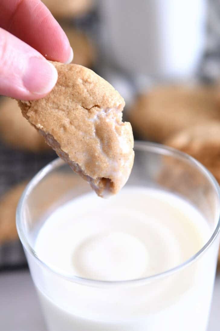 Half peanut butter cookie dipped in glass of milk.