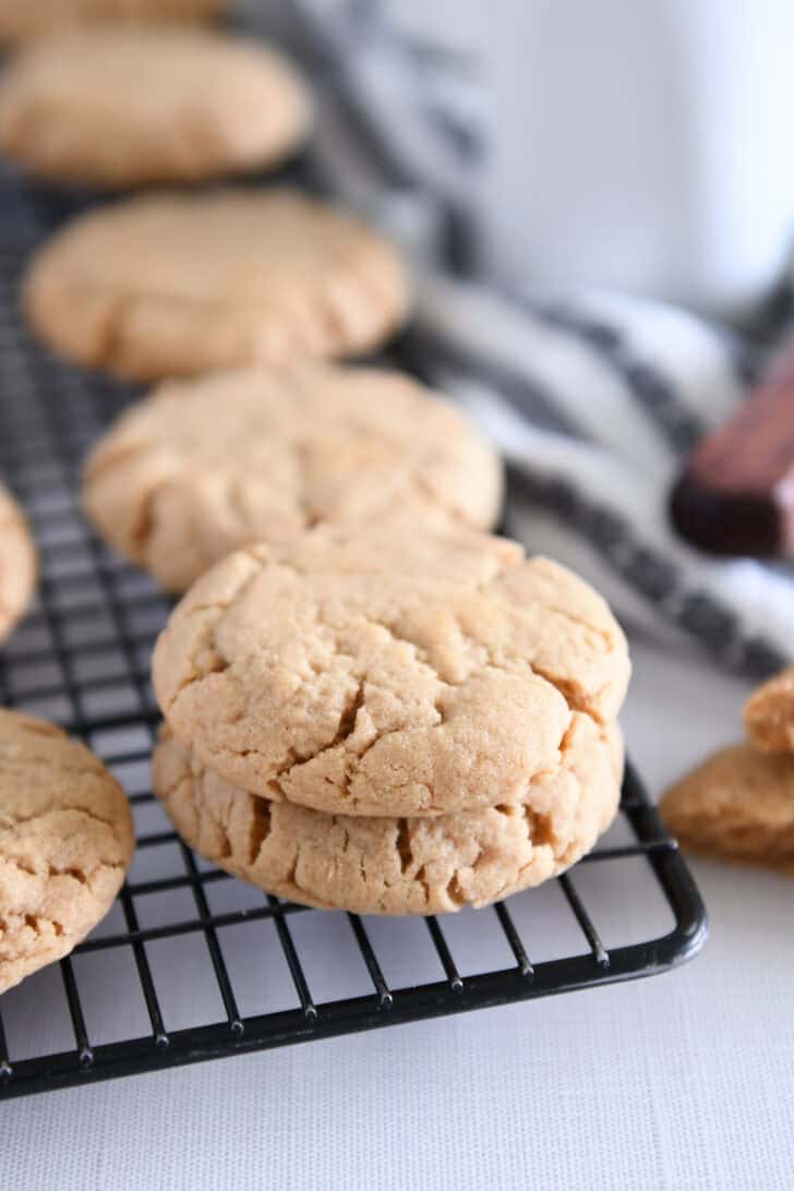 Two peanut butter cookies stacked on cooling rack.