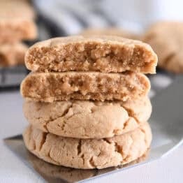 Four stacked peanut butter cookies on flat metal spatula.
