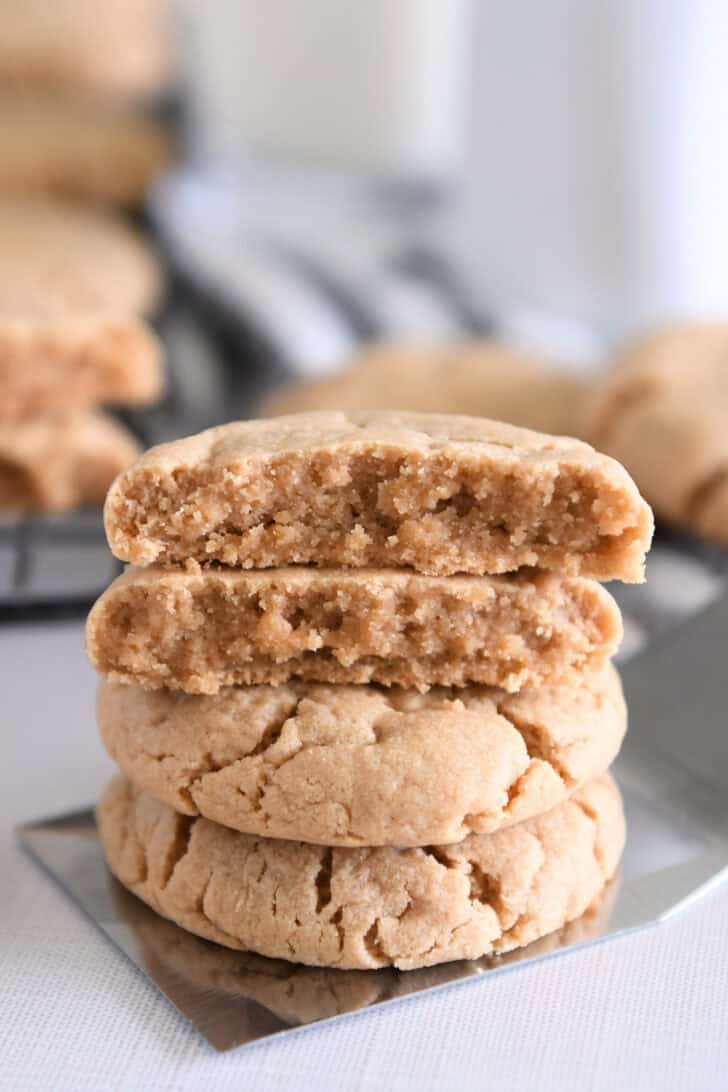 Four stacked peanut butter cookies on flat metal spatula.
