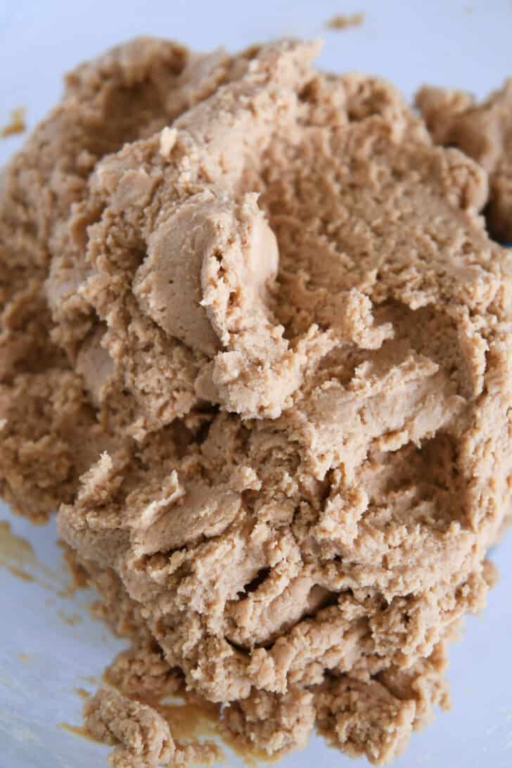 Mass of peanut butter cookie dough in glass bowl.