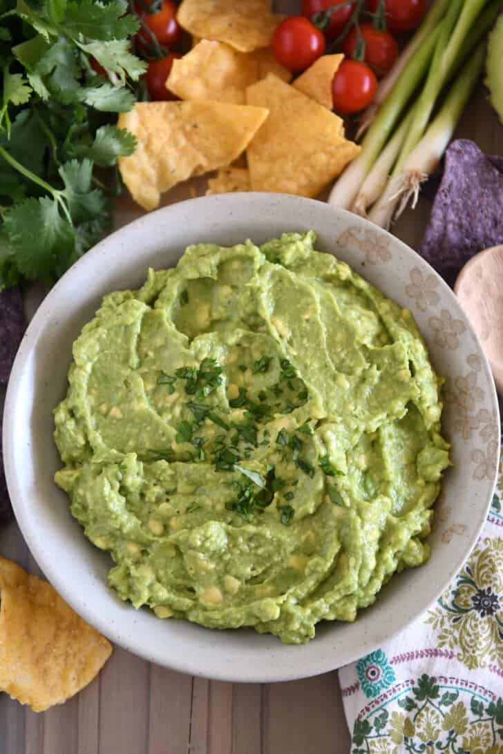 Top down view of homemade guacamole in tan bowl with chopped cilantro.
