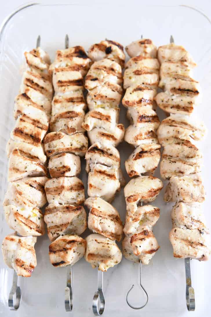 Glass 9X13-inch pan with skewers of cooked chicken.