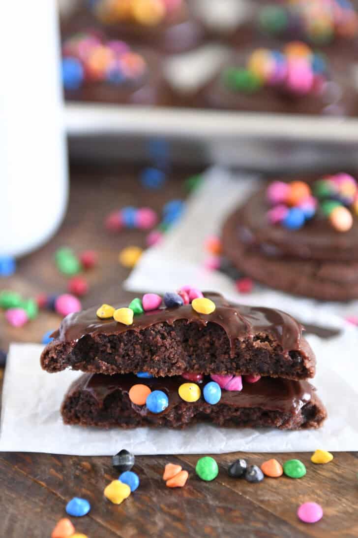Two cosmic brownie cookie halves stacked on each other on piece of white parchment paper.