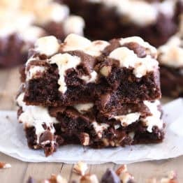 Rocky road chocolate cookie bar split in half and stacked on white parchment paper.