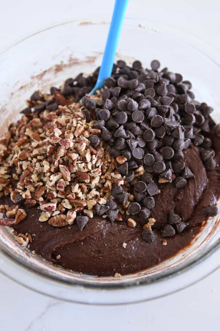 Chopped pecans and chocolate chips on top of chocolate cookie batter.