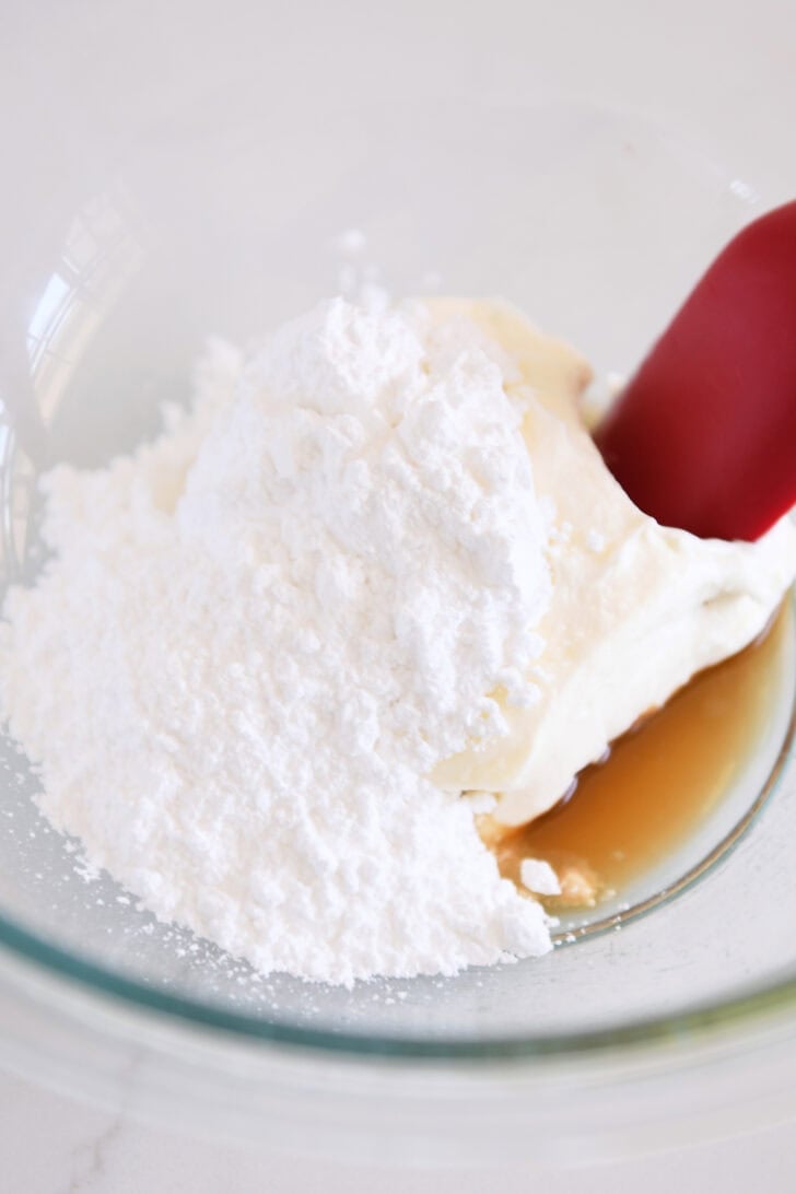 Powdered sugar, cream cheese and vanilla in glass bowl.