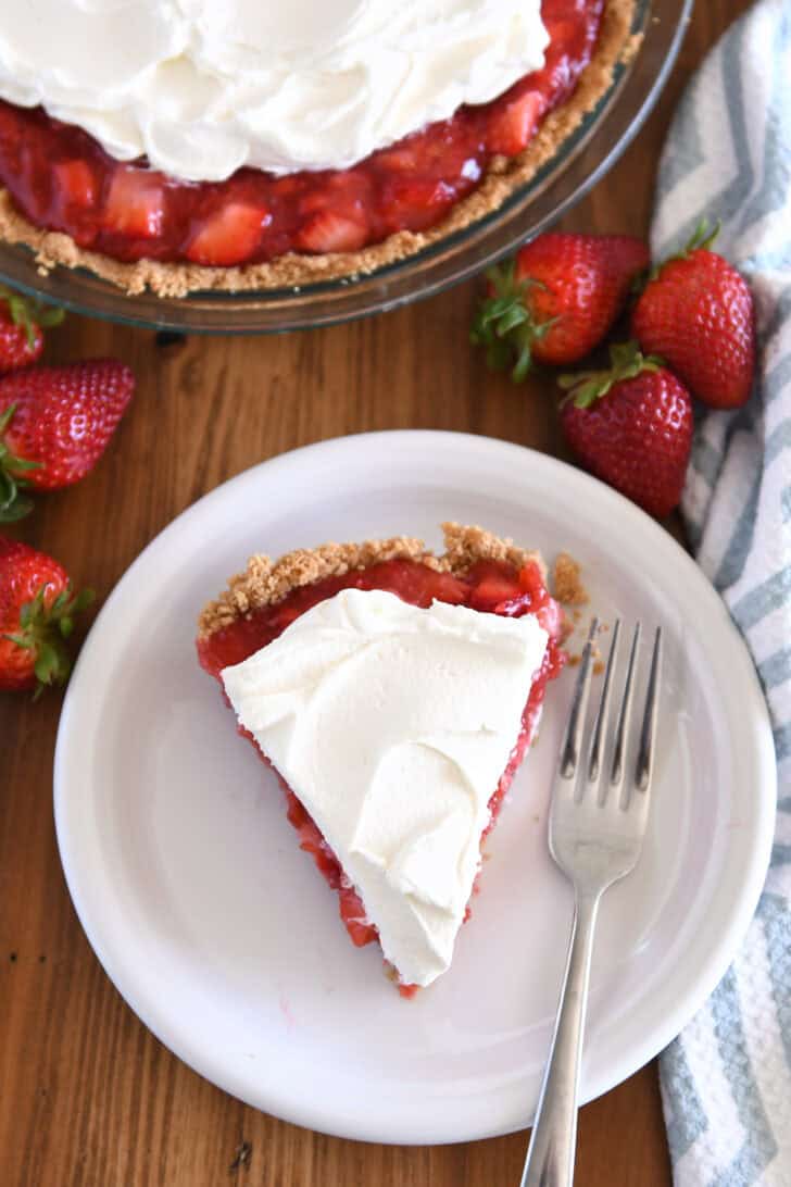 Top down view of slice of strawberry cream pie on white plate with fork.