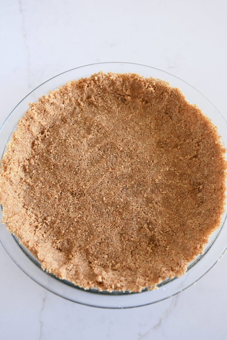 Baked graham cracker crust in glass pie plate.