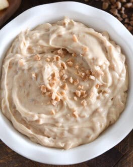 White bowl with toffee apple dip and toffee bits on top.