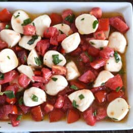 A white dish full of tomato mozzarella caprese salad.